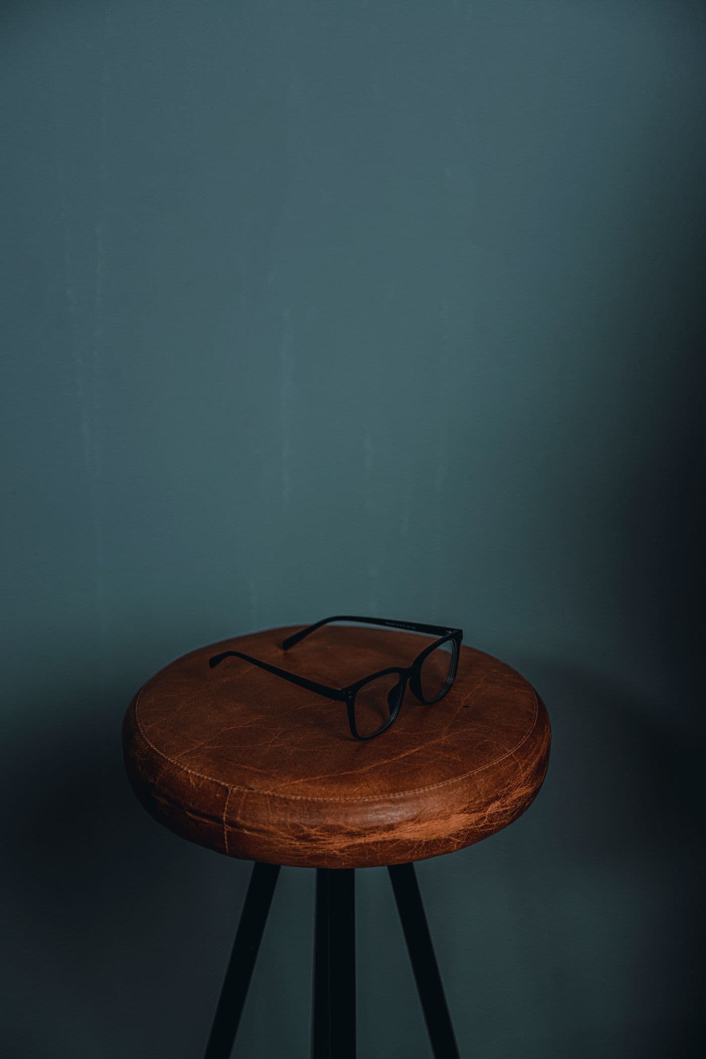 Black eyeglasses resting on a leather stool